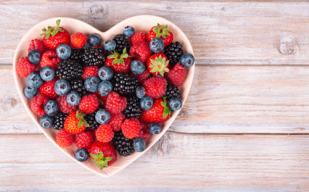Healthy heart symbol made of berries on wooden table